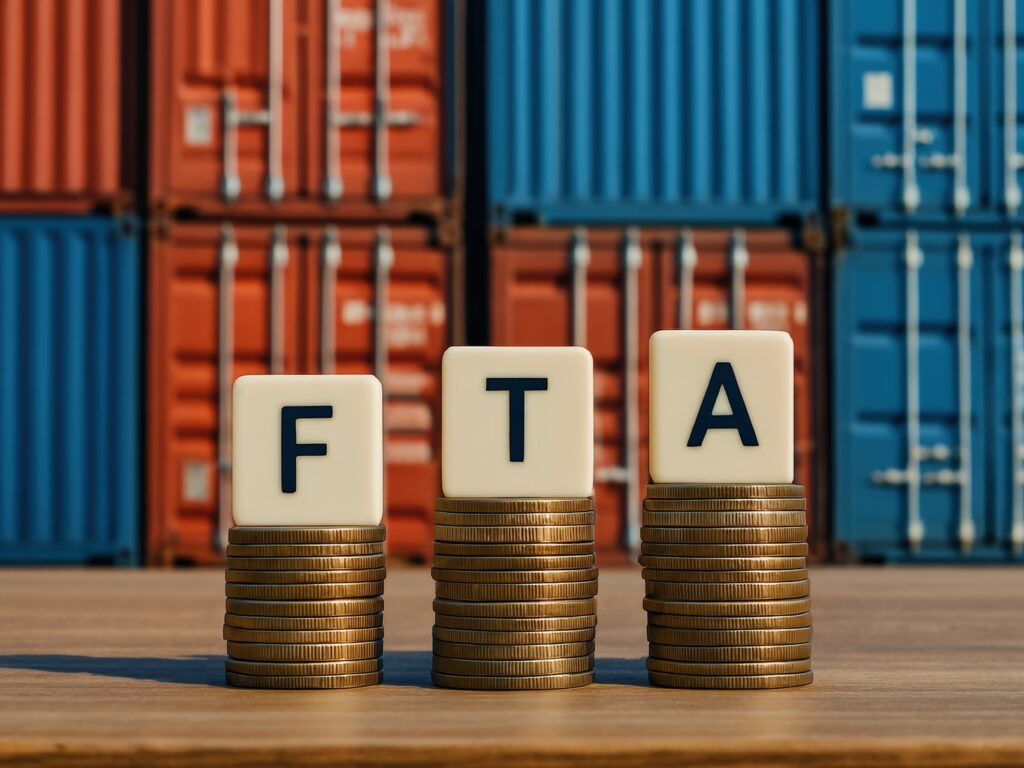 Close up of tiles that spell FTA with a backdrop of cargo containers