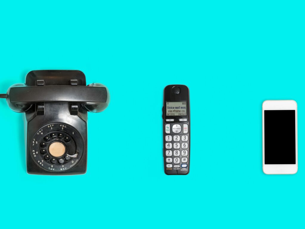 Three phones from rotary dial through wireless to modern smartphone