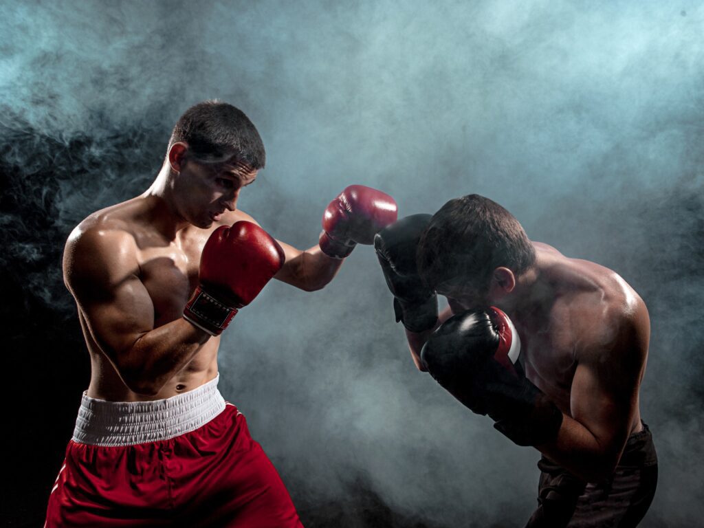Two boxers fighting in a boxing ring with a dark background.